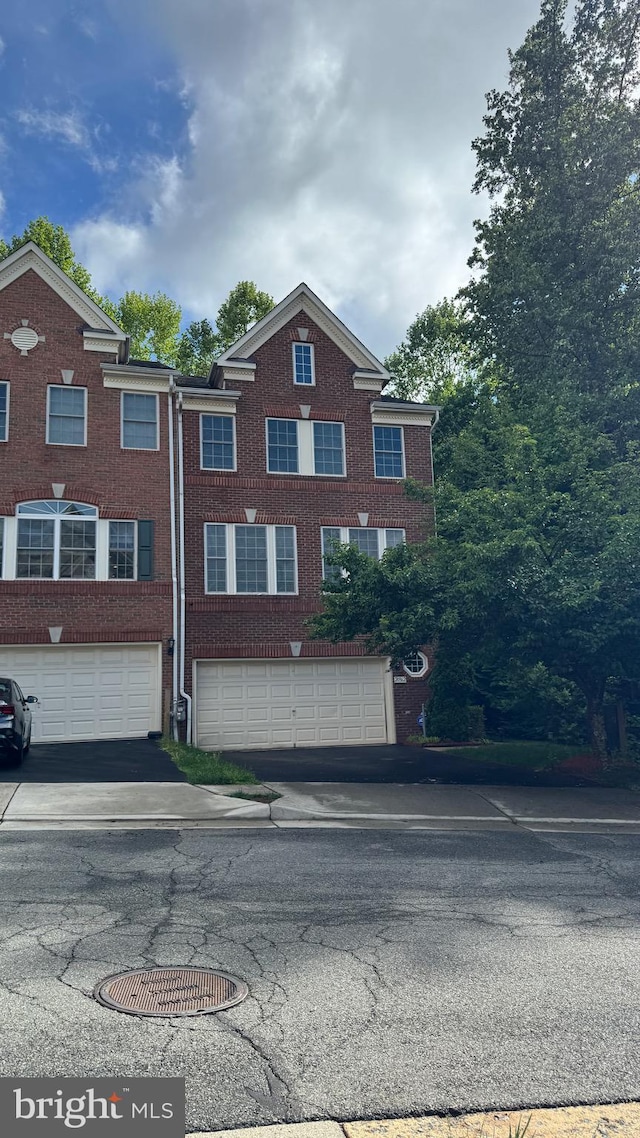 multi unit property with driveway, a garage, and brick siding