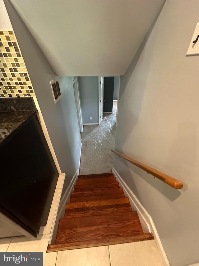 stairway featuring baseboards and tile patterned flooring