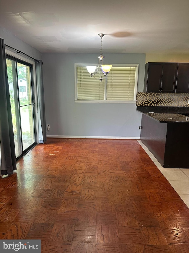 unfurnished dining area with a chandelier and baseboards