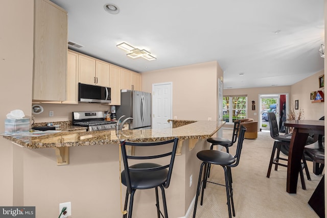 5942 Kimberly Anne Way, Alexandria, VA 22310 - kitchen featuring stainless steel appliances, light brown cabinetry, a peninsula, light carpet, and light stone countertops