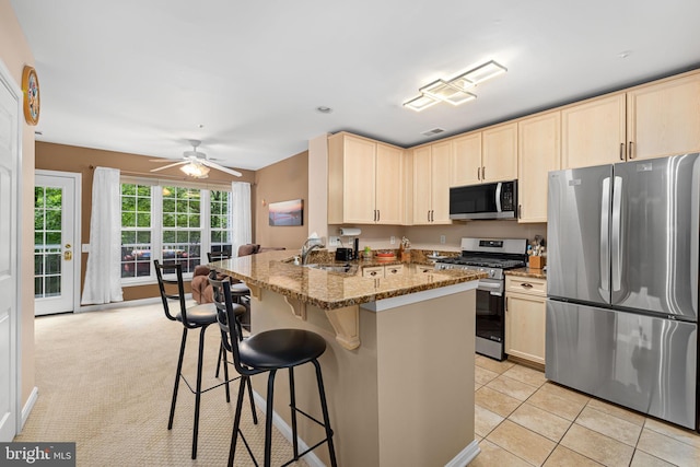 5942 Kimberly Anne Way, Alexandria, VA 22310 - kitchen with stainless steel appliances, a sink, light brown cabinetry, a peninsula, and a kitchen breakfast bar