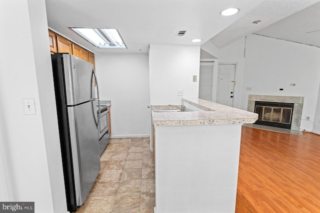 1013 Fallcrest Ct Unit 4-203, Bowie, MD 20721 - kitchen with freestanding refrigerator, a peninsula, light countertops, brown cabinetry, and a fireplace