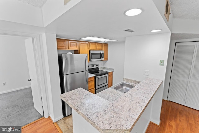 1013 Fallcrest Ct Unit 4-203, Bowie, MD 20721 - kitchen with appliances with stainless steel finishes, a sink, a peninsula, light wood-style flooring, and baseboards