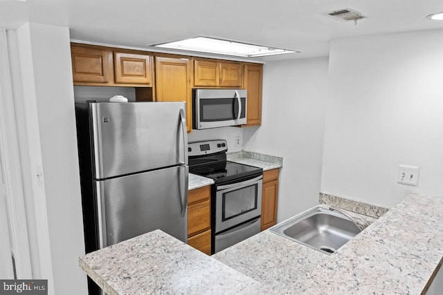 1013 Fallcrest Ct Unit 4-203, Bowie, MD 20721 - kitchen featuring appliances with stainless steel finishes, a sink, brown cabinetry, light countertops, and a peninsula
