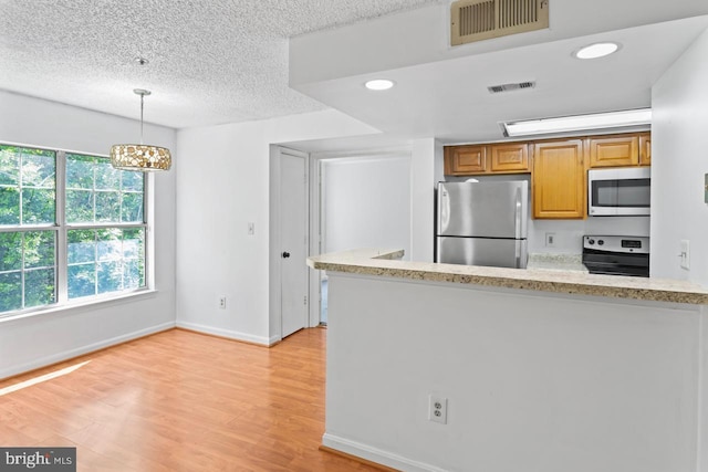 1013 Fallcrest Ct Unit 4-203, Bowie, MD 20721 - kitchen featuring stainless steel appliances, brown cabinets, light wood-style flooring, decorative light fixtures, and a textured ceiling