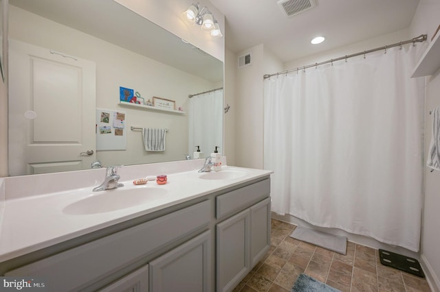 bathroom with double vanity, stone finish flooring, and recessed lighting