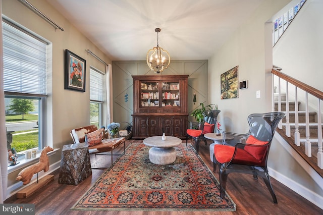 sitting room with wood finished floors, a chandelier, baseboards, and stairway