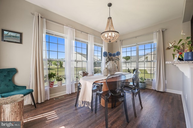 dining area featuring a chandelier, dark wood finished floors, and baseboards