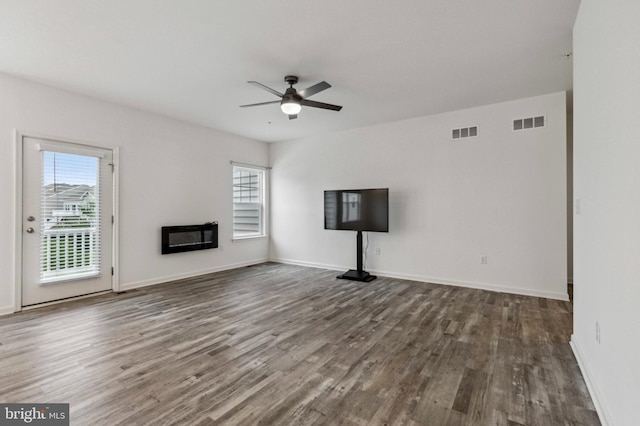 unfurnished living room featuring a ceiling fan, plenty of natural light, wood finished floors, and a glass covered fireplace