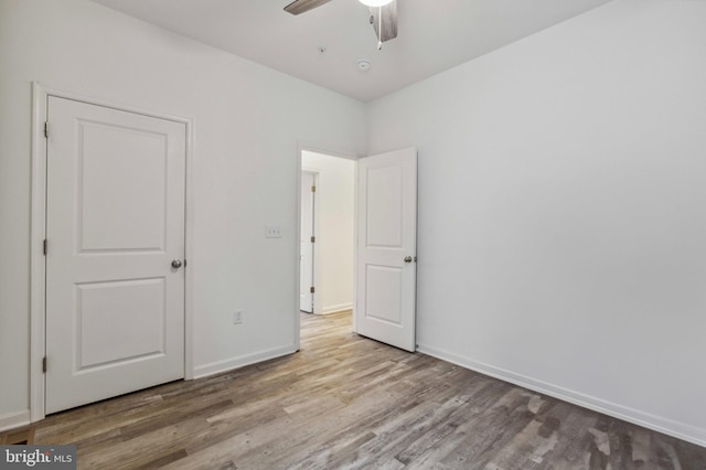 unfurnished bedroom with wood finished floors, baseboards, and a ceiling fan