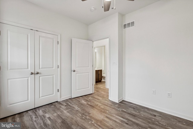 unfurnished bedroom featuring wood finished floors, baseboards, a closet, and a ceiling fan