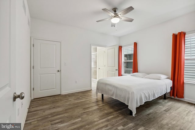 bedroom with wood finished floors, multiple windows, baseboards, and connected bathroom
