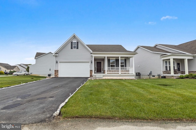 view of front of property with covered porch, asphalt driveway, a front yard, and an attached garage