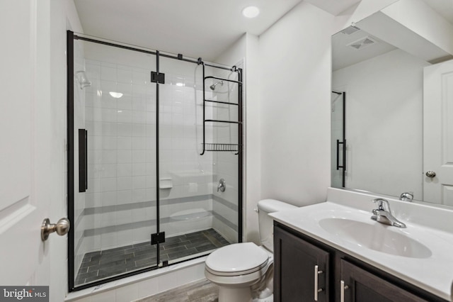 bathroom featuring toilet, a stall shower, and vanity