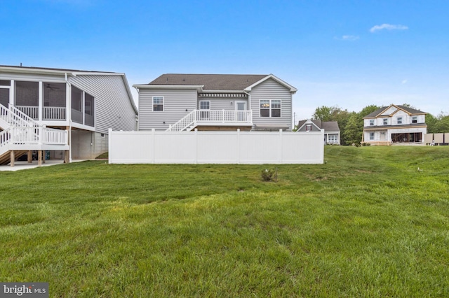 rear view of property featuring stairway, a sunroom, and a wooden deck
