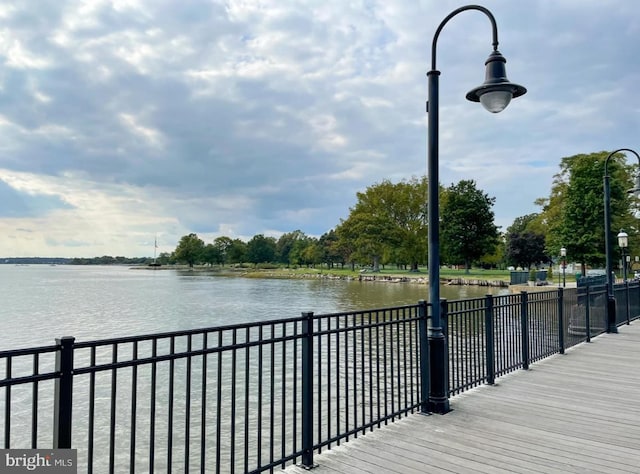 wooden deck featuring a water view and fence