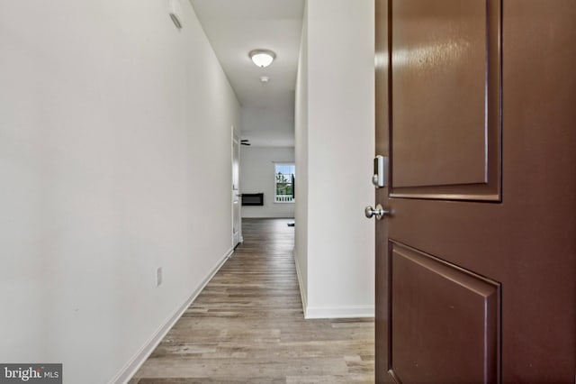 corridor with light wood-type flooring and baseboards