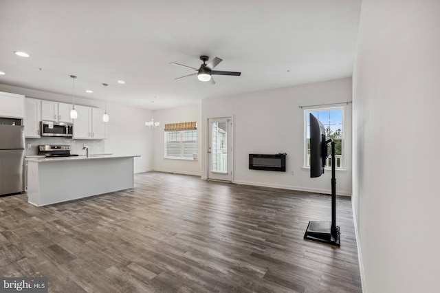unfurnished living room featuring recessed lighting, ceiling fan, dark wood finished floors, a sink, and baseboards