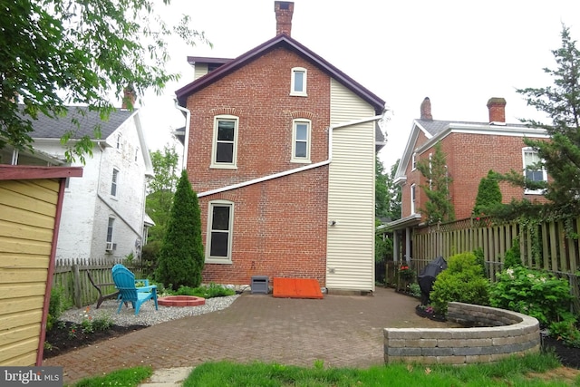 145 S Washington St, Greencastle, PA 17225 - back of property featuring a patio area, brick siding, a fenced backyard, and a fire pit