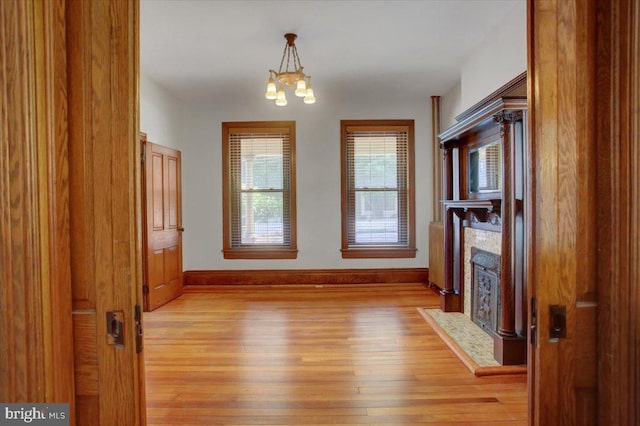 145 S Washington St, Greencastle, PA 17225 - unfurnished dining area with light wood-style floors, a chandelier, baseboards, and a fireplace with flush hearth