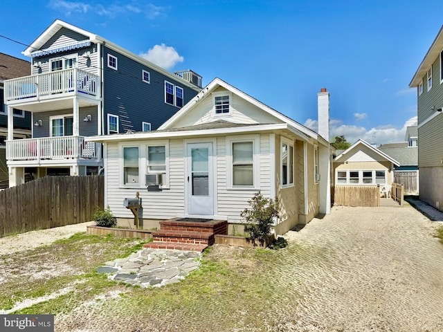 view of front of house with a chimney, a fenced backyard, and cooling unit