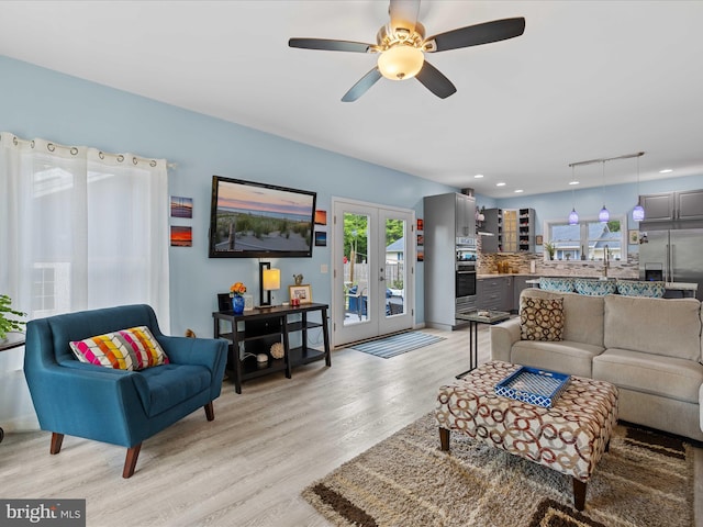 living area with healthy amount of natural light, light wood-type flooring, french doors, a ceiling fan, and recessed lighting