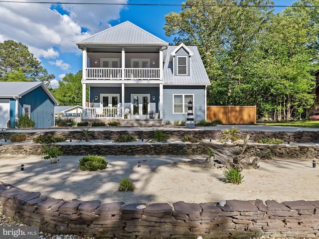 rear view of property featuring french doors, a balcony, metal roof, and covered porch