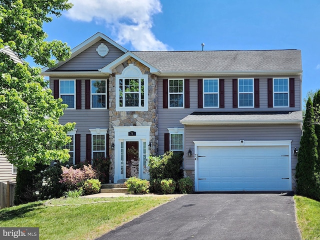 colonial home with stone siding, an attached garage, asphalt driveway, and a front yard
