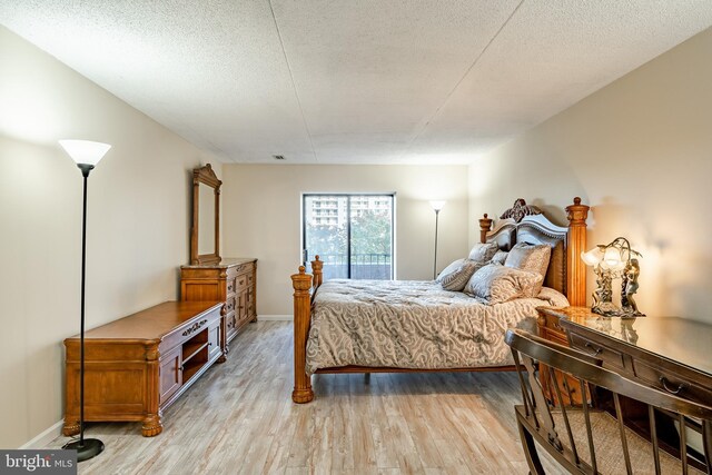 bedroom featuring light wood finished floors, baseboards, and a textured ceiling