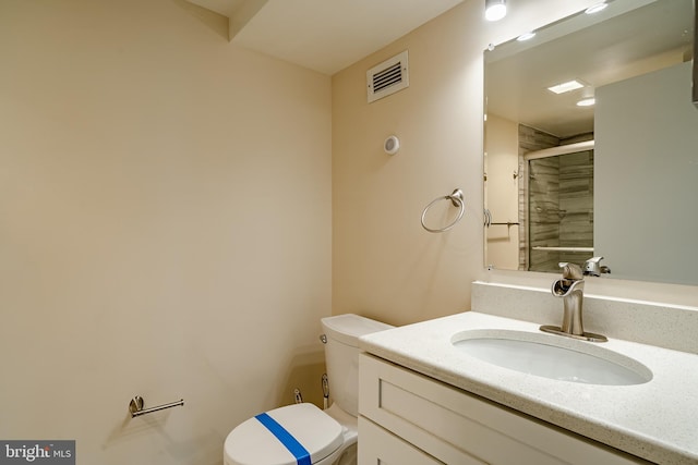 bathroom with toilet, a stall shower, and vanity