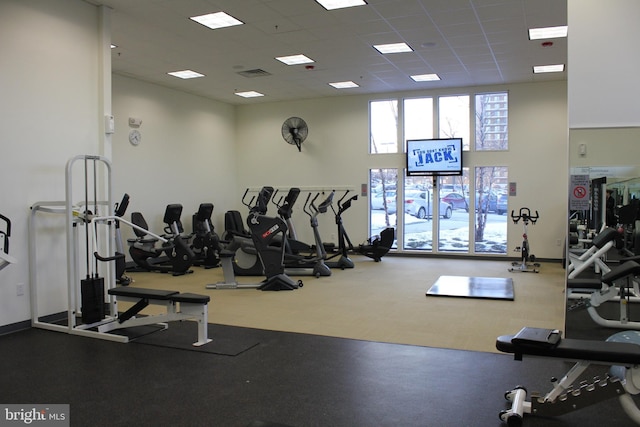 exercise room featuring a drop ceiling and a high ceiling