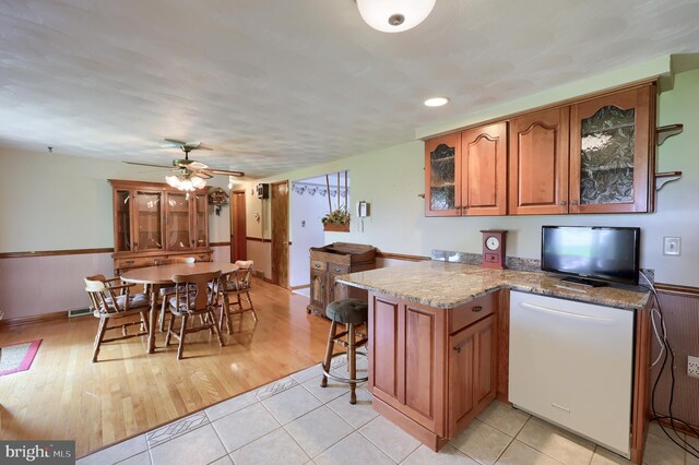 630 E Canal Rd, York, PA 17404 - kitchen with brown cabinetry, light stone countertops, glass insert cabinets, a ceiling fan, and a peninsula