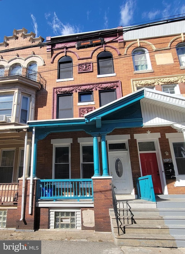 view of front facade featuring brick siding and a porch