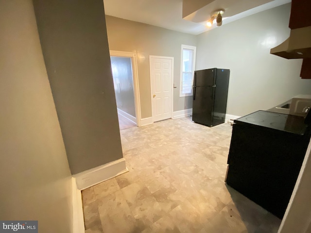 kitchen featuring freestanding refrigerator, baseboards, and exhaust hood