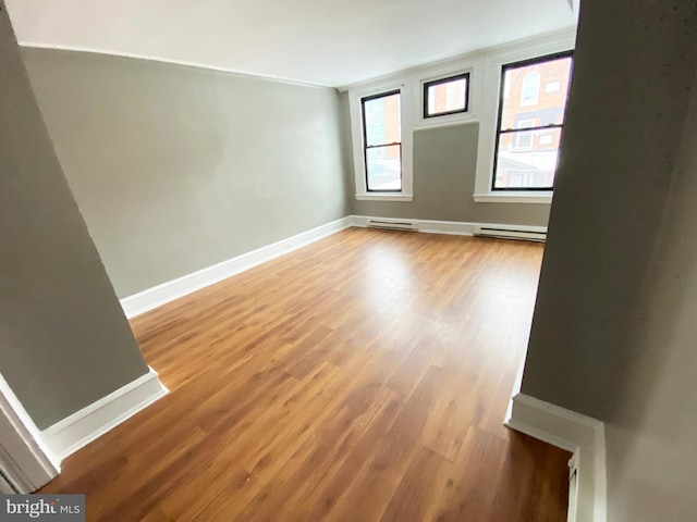 unfurnished room with baseboards, light wood-type flooring, and baseboard heating