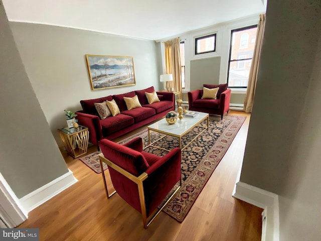 living area with wood finished floors, a baseboard heating unit, and baseboards