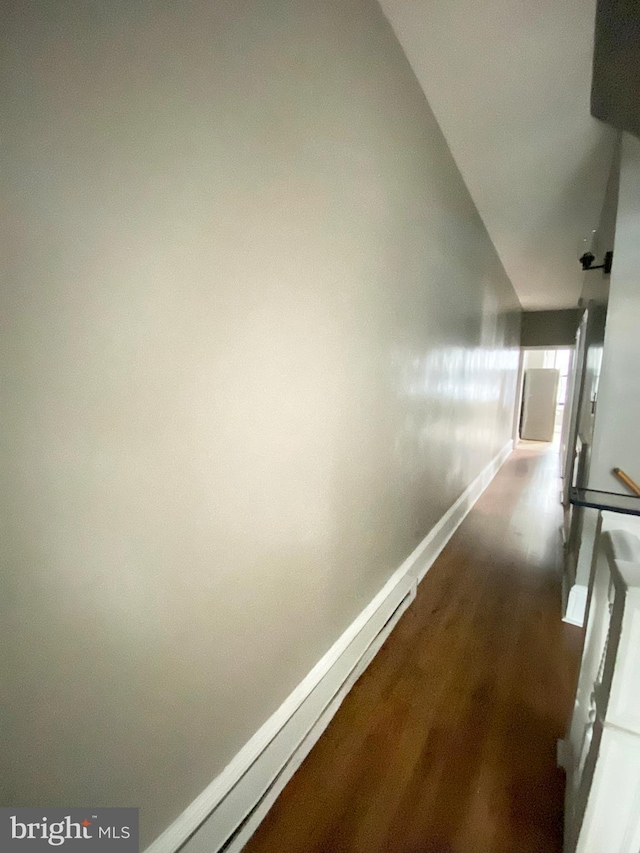 corridor featuring baseboards and dark wood-type flooring