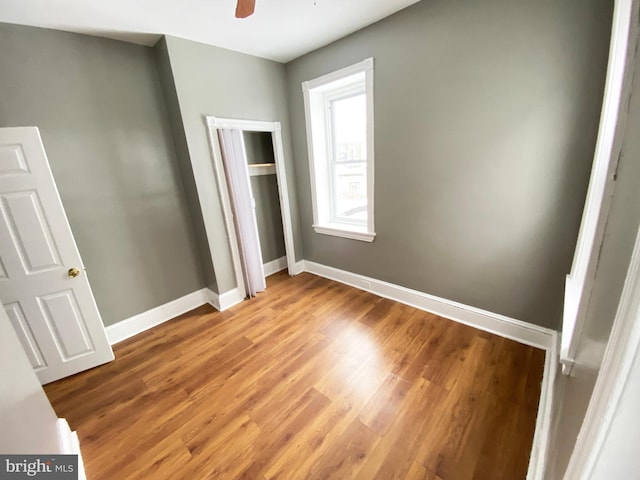unfurnished bedroom featuring light wood-style flooring, baseboards, a closet, and a ceiling fan