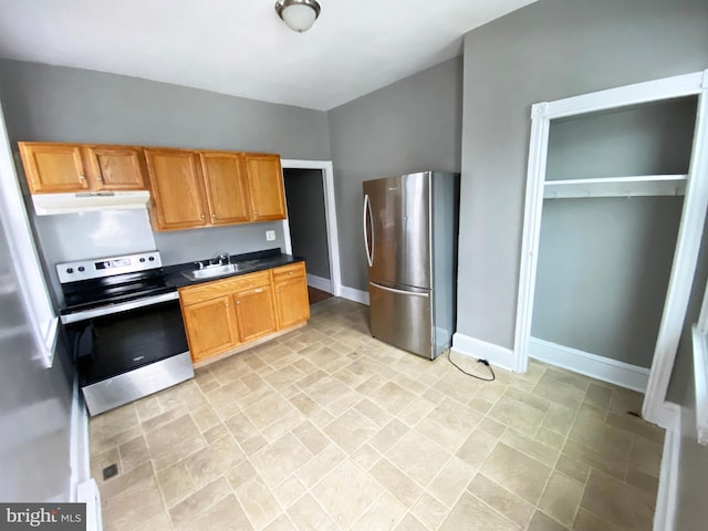 kitchen featuring stainless steel appliances, baseboards, dark countertops, under cabinet range hood, and a sink