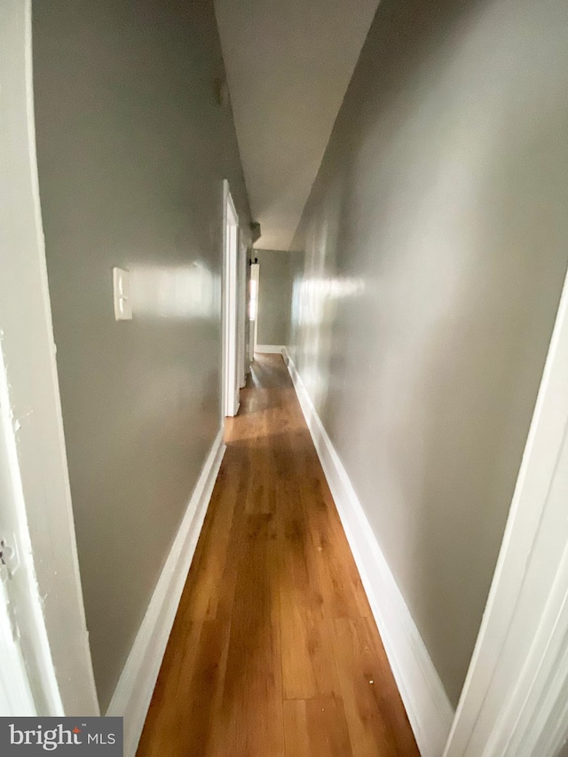 hallway featuring baseboards and wood finished floors