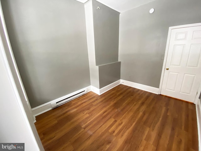 unfurnished room featuring baseboard heating, dark wood finished floors, and baseboards