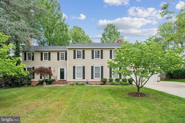 view of front of house with driveway, a chimney, a garage, and a front yard