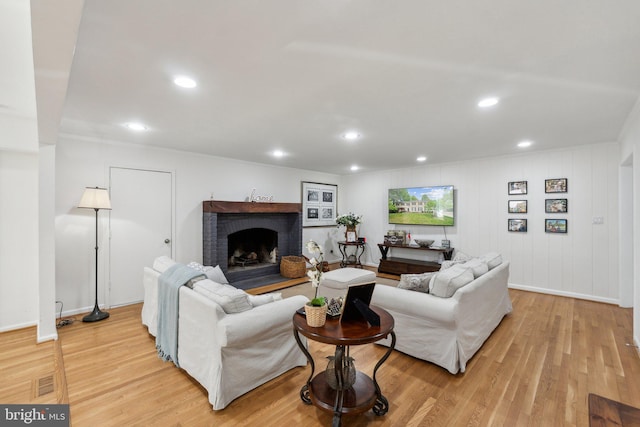 living area featuring light wood-style flooring, a fireplace, recessed lighting, and baseboards