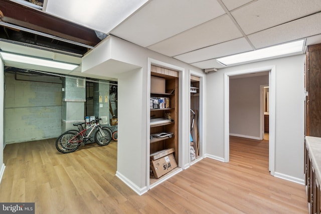hallway featuring light wood-type flooring, built in features, and baseboards