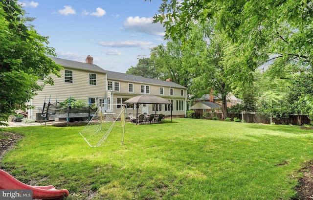 rear view of property featuring a gazebo, a chimney, and a deck