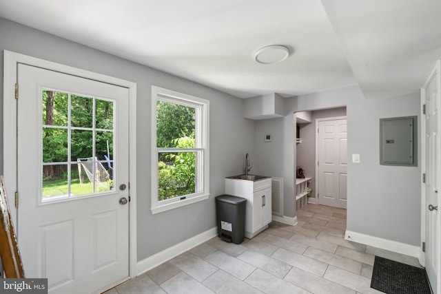 doorway featuring electric panel, plenty of natural light, baseboards, and light tile patterned floors