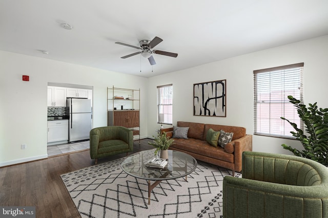 living area featuring wood finished floors, a ceiling fan, and baseboards