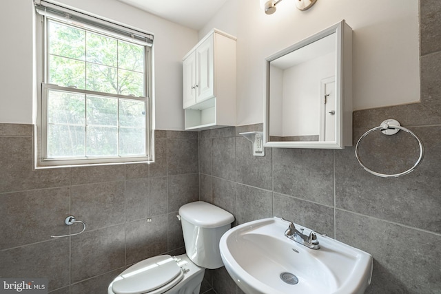 bathroom with tile walls, a sink, and toilet