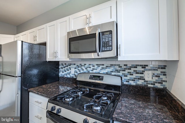 kitchen with stainless steel appliances, white cabinets, decorative backsplash, and dark stone counters