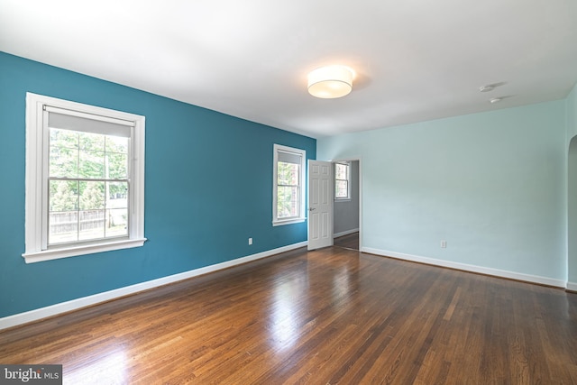 spare room featuring dark wood-type flooring and baseboards